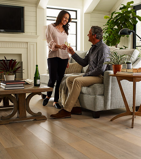 Couple sharing drinks in a living room with wood-look luxury vinyl flooring from Southwest Floors in Seven Hills, OH