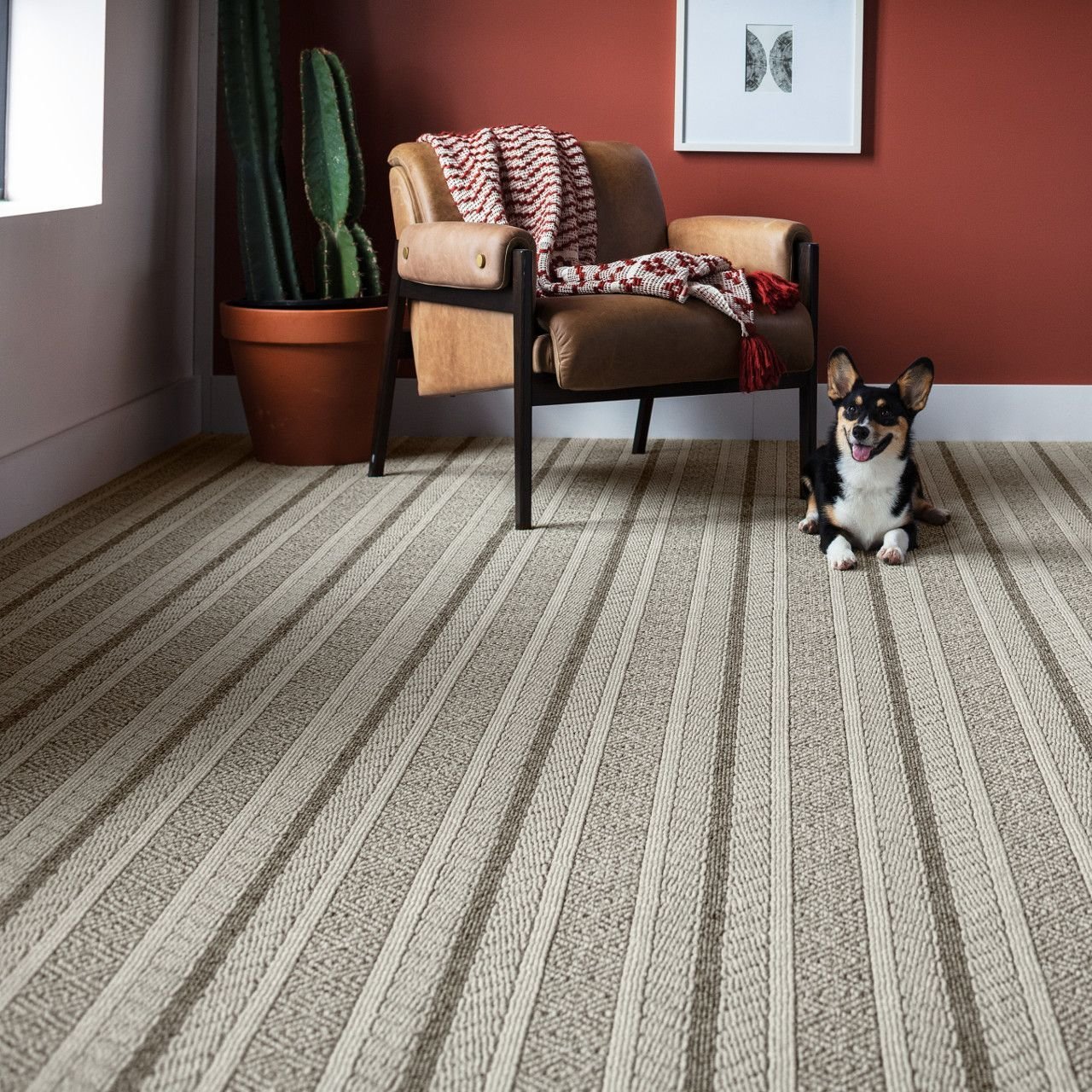 Dog next to a brown armchair in a living room with red walls and patterned Anderson Tuftex carpet from Southwest Floors in Seven Hills, OH